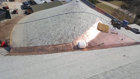 copper cricket being installed on a turret roof