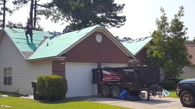 roof replacement in progress with green synthetic underlayment on the deck