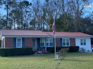 brick home with red multi-rib metal roofing