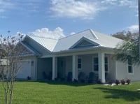 stucco home with 2 car garage and a galvalume metal roof