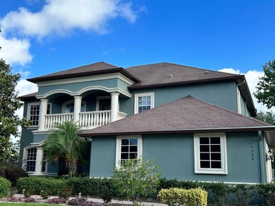 Split-level green stucco home with hip shingle roof