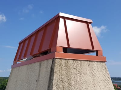 red chimney cap and windscreen on a stucco chimney