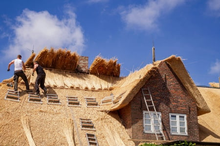 men repairing thatched roof