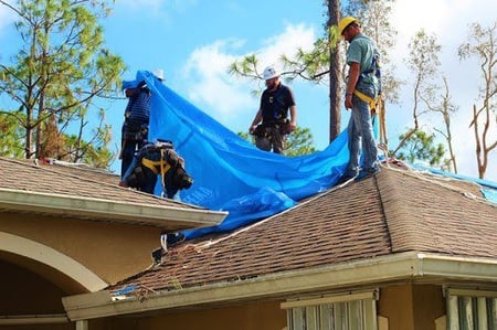 roofers placing tarp on a roof